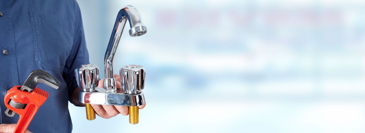 Grifo de baño cromado con dos dispensadores de jabón y una llave inglesa roja sobre un fondo azul.