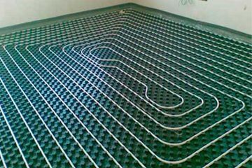 Tuberías verdes de calefacción por suelo radiante dispuestas en una habitación antes de que se termine el suelo.