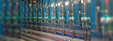Hilera de válvulas y tuberías industriales azules en una fábrica o sistema de servicios públicos.