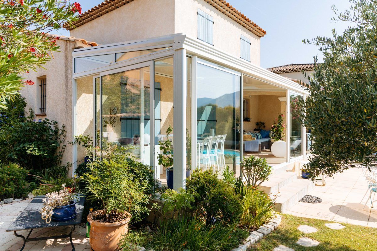 Une maison avec une jolie véranda, laissant entrer une abondante lumière naturelle et offrant une connexion harmonieuse avec l'extérieur.