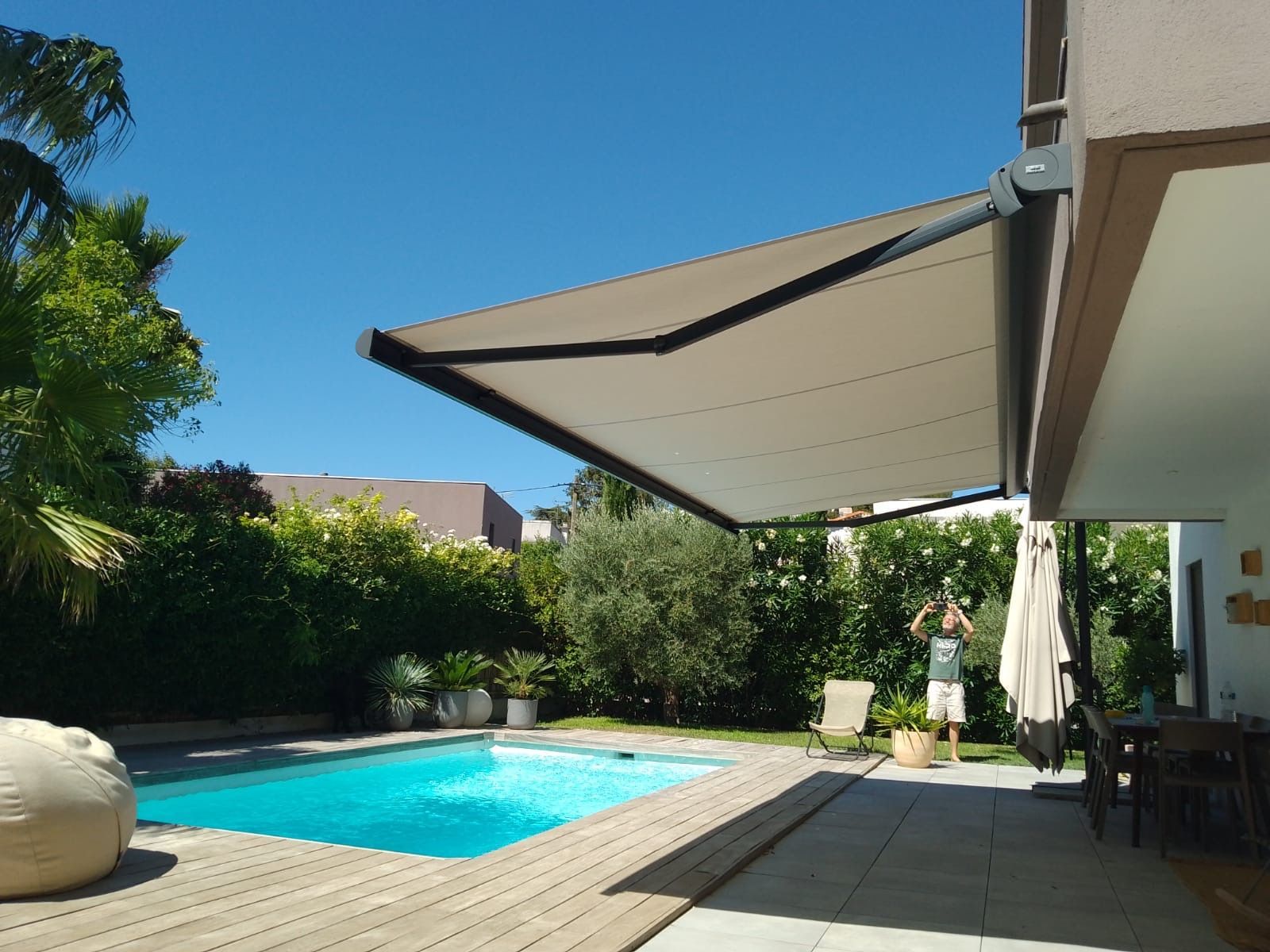 Un store s'étend au-dessus d'une terrasse au bord de la piscine. 