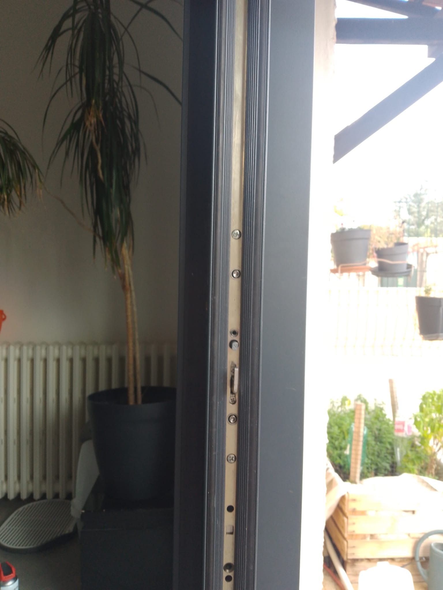 Vue verticale d'un cadre de porte sombre fermé. À l'intérieur, on aperçoit divers mécanismes de verrouillage.