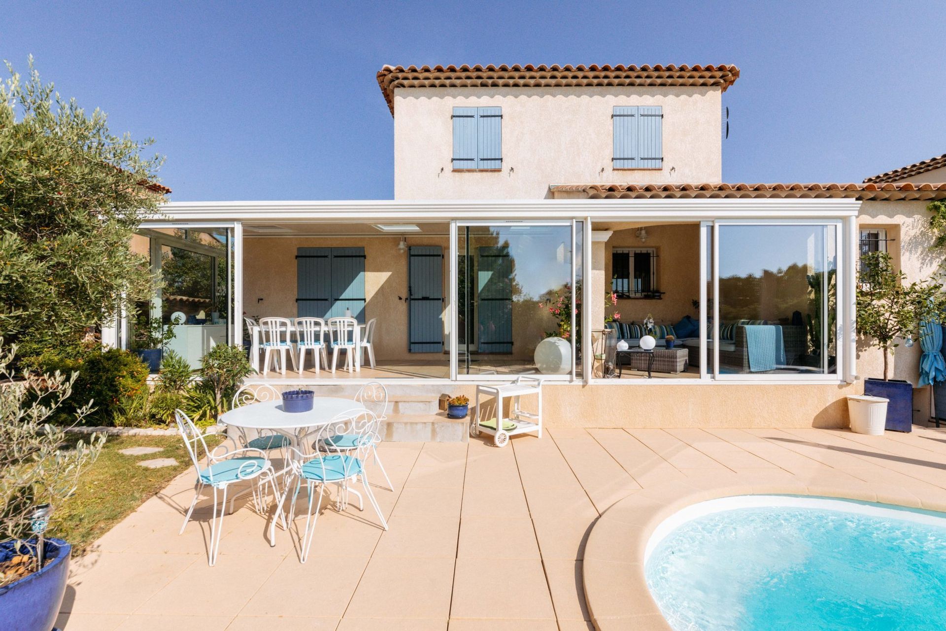 Une maison avec une grande véranda avec piscine et table à l'extérieur. Elle met en valeur des éléments de l'immobilier, notamment dans un cadre de villégiature, soulignant le potentiel de détente et de loisirs de la propriété.