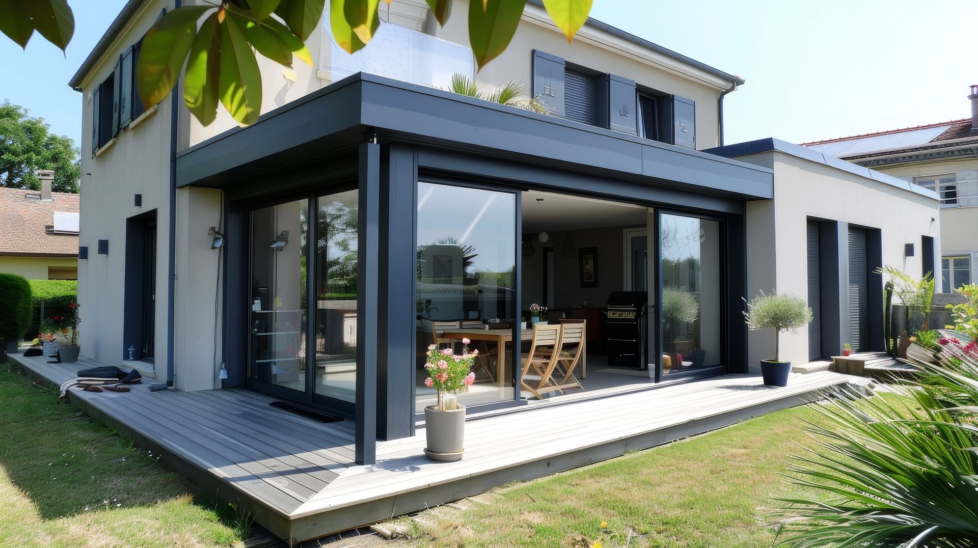 Véranda moderne attachée à une maison qui comporte une terrasse et un jadin, on y voit une table et des chaises