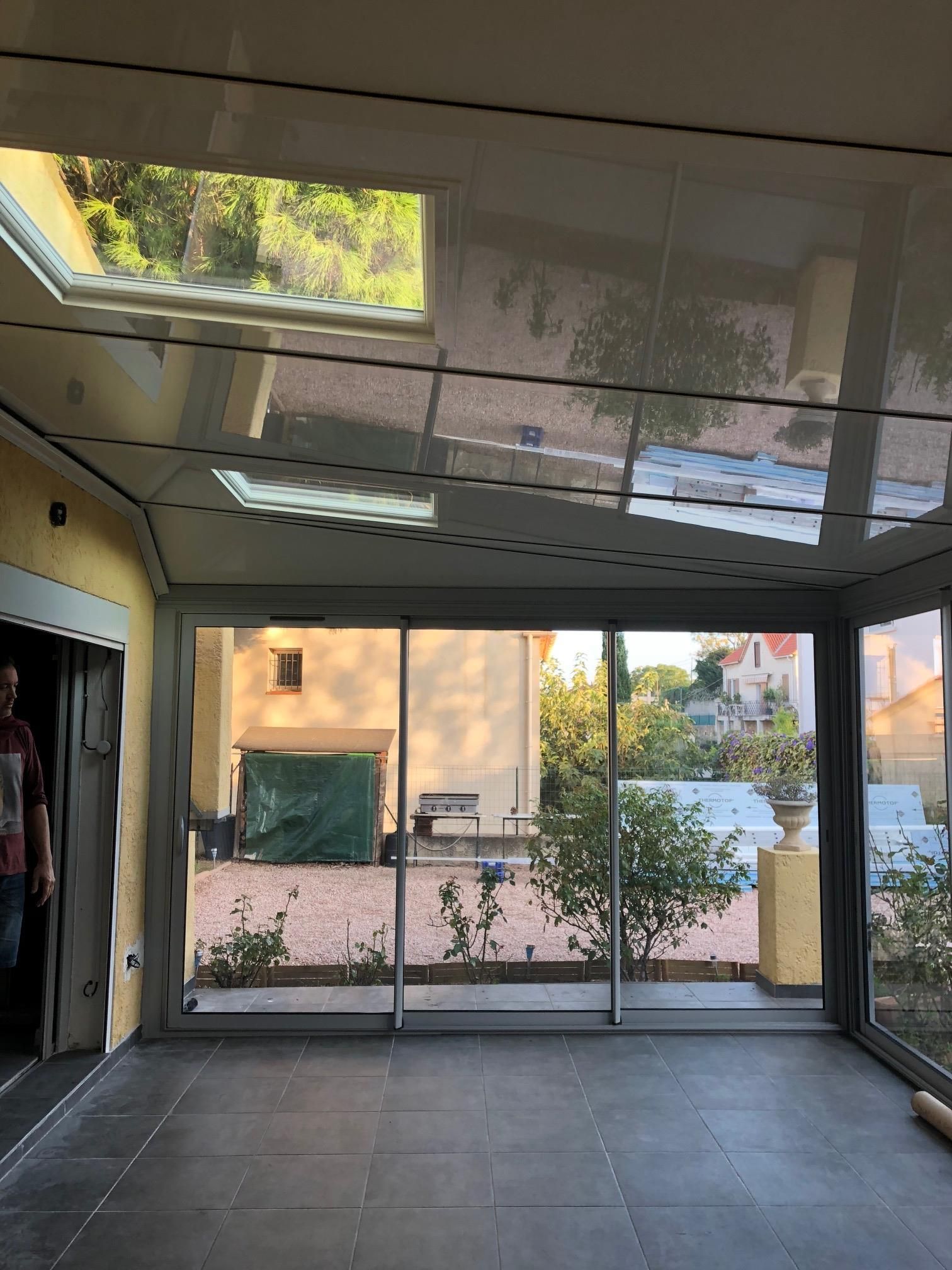 Intérieur d'une véranda avec une vue sur la terrasse extérieur et plusieurs plantes