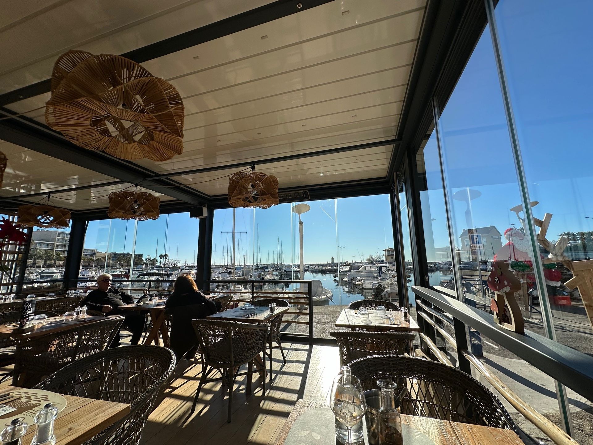 Grande véranda d'un restaurant avec plusieurs tables et chaises et avec vue sur le vieux port