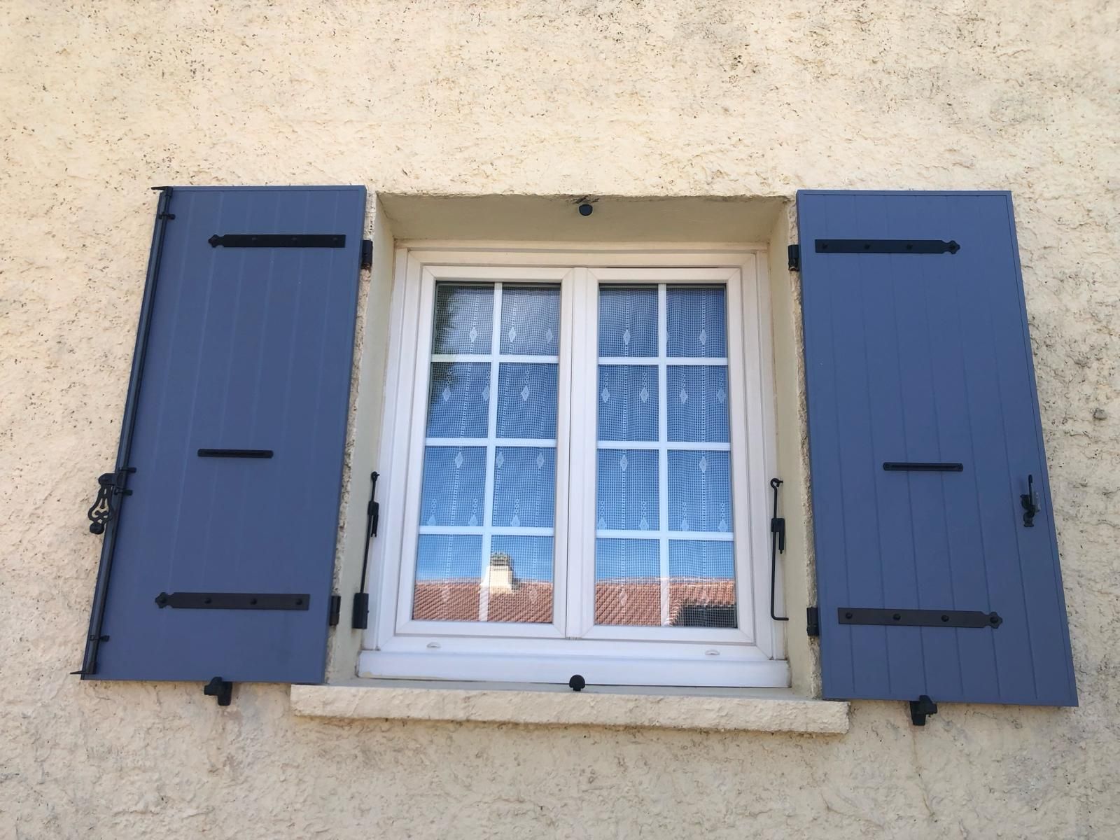 Fenêtre en PVC blanc avec des volets battants ouverts