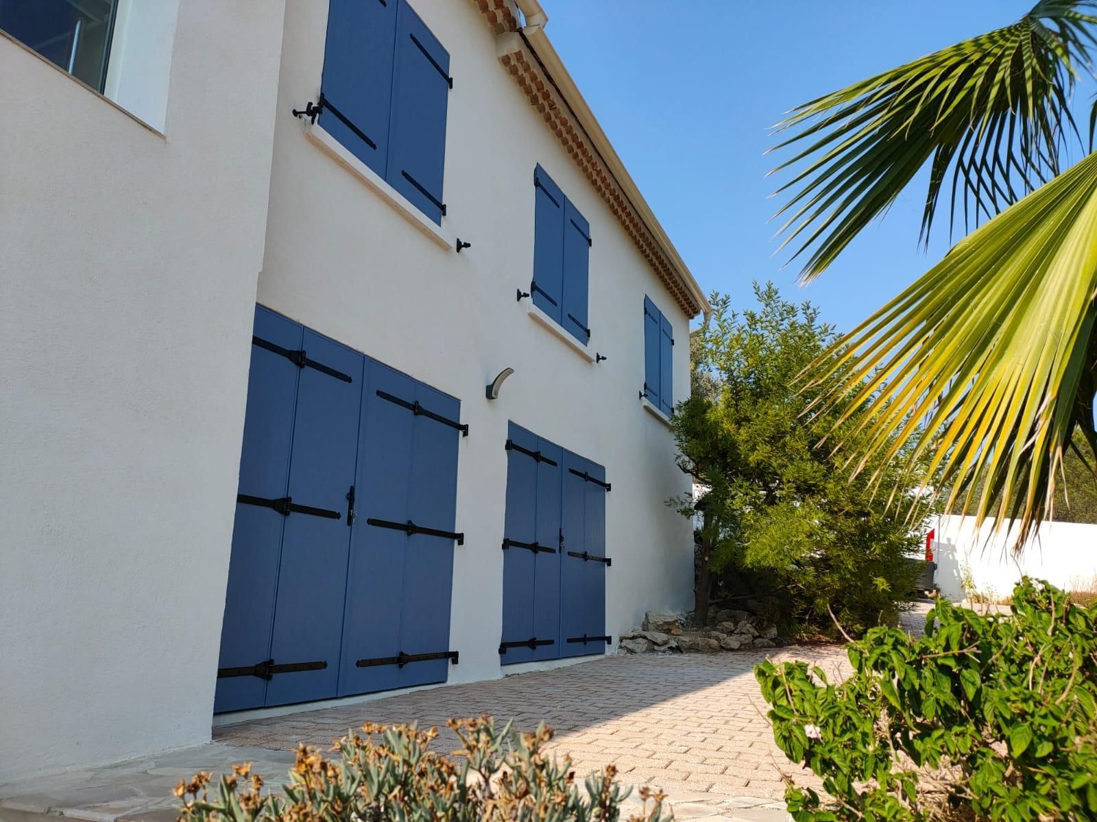 Façade de maison avec des volets de fenêtres et des volets de portes fenêtres tous de couleur bleu