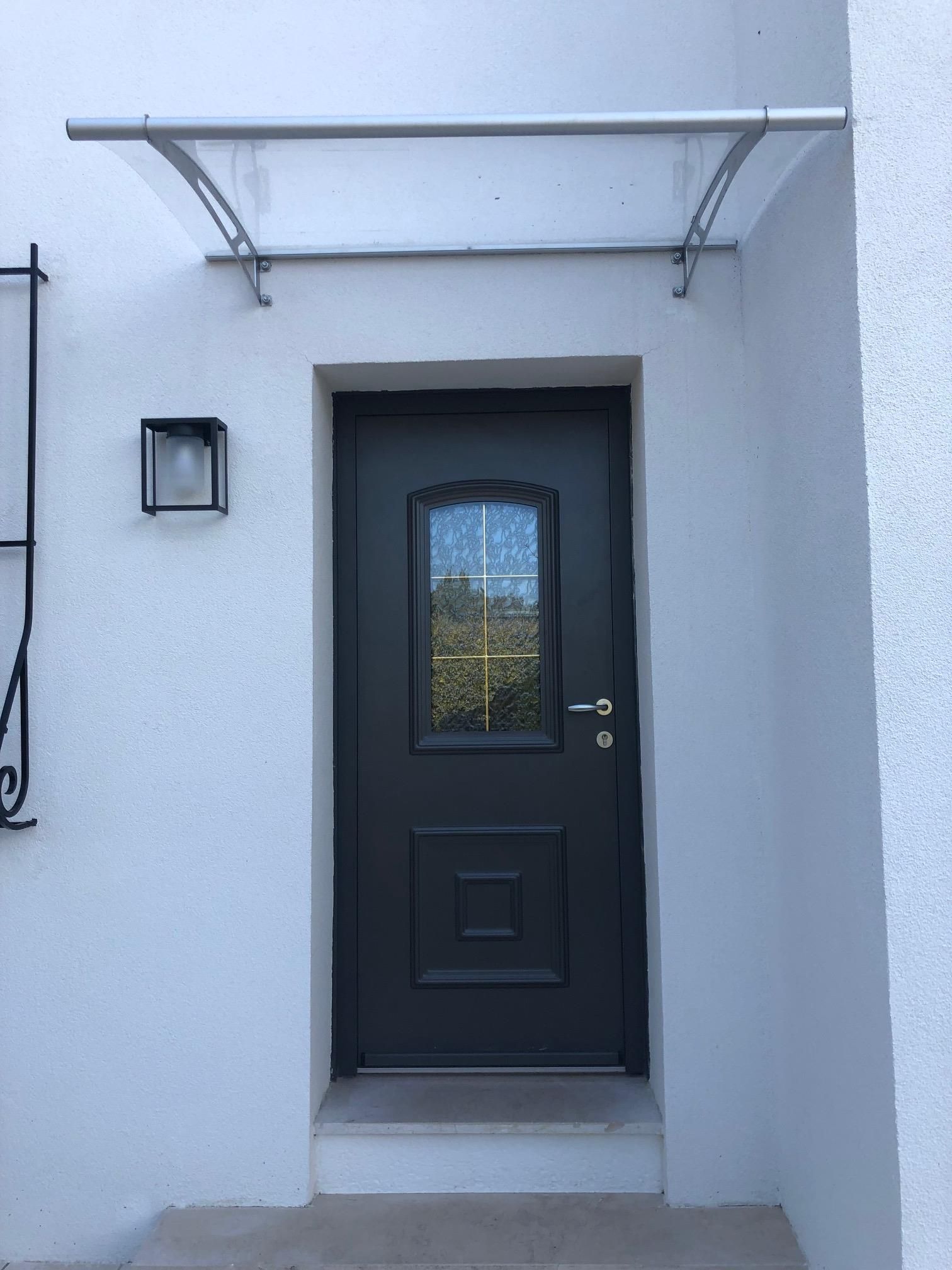Porte d'entrée noire sur une façade de maison blanche