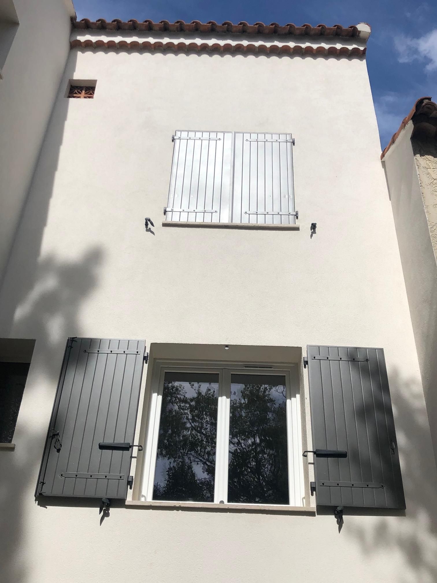 façade d'une maison avec deux fenêtres aux volets battants, l'un ouvert et l'autre fermé