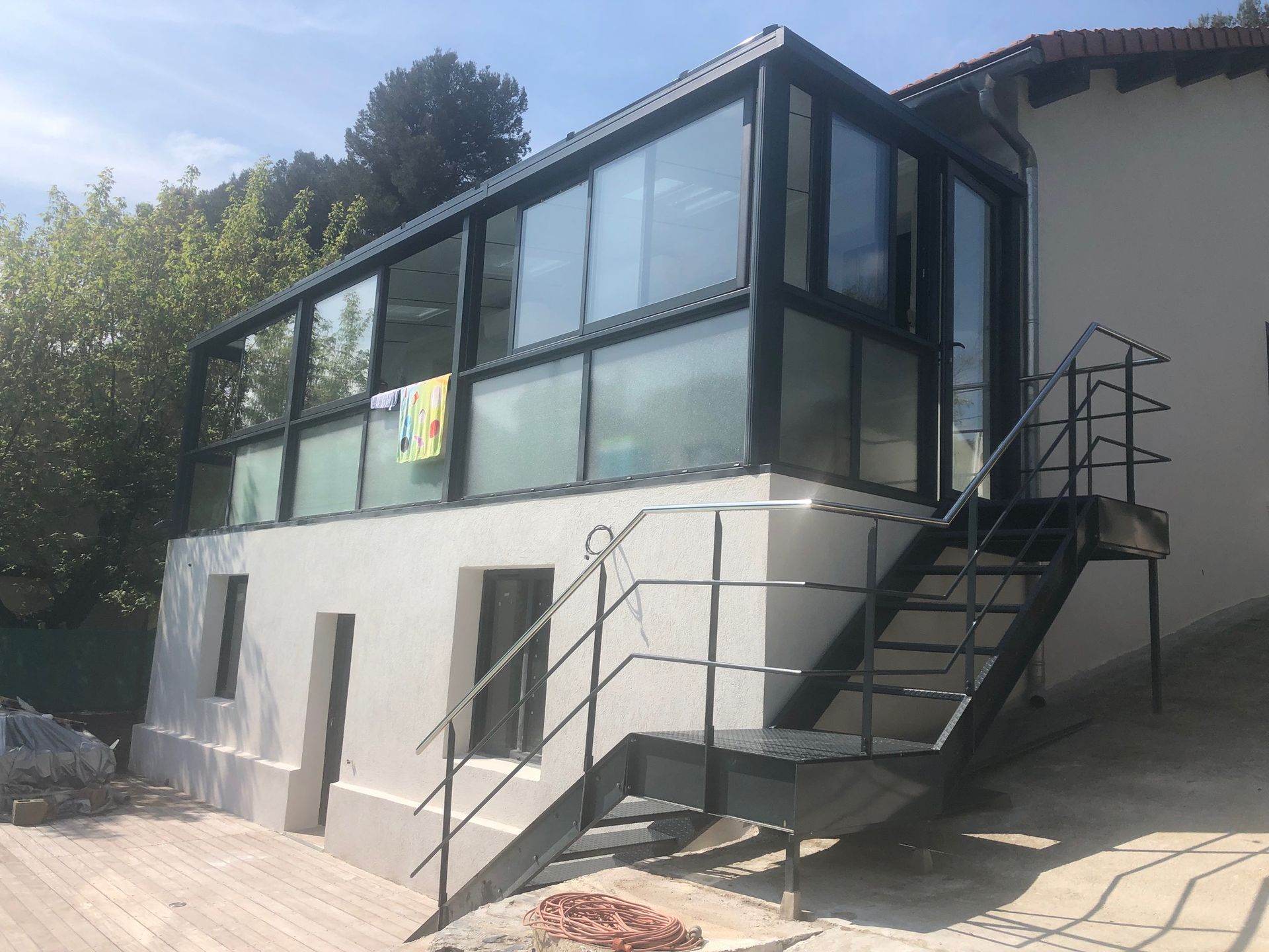 Un bâtiment doté d'un escalier donnant sur une véranda, suggérant l'accès aux différents niveaux. La structure, située en extérieur, met en valeur des éléments architecturaux qui contribuent à son design général.
