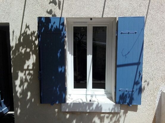 Fenêtre avec des volets battants bleus ouverts