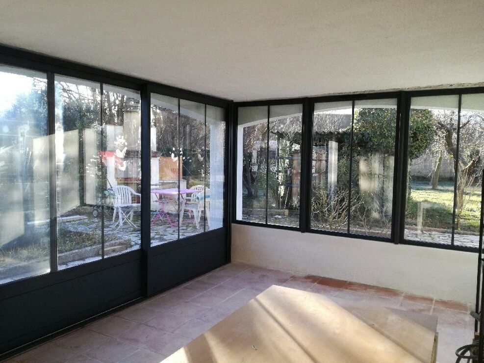 Une grande pièce vide avec de grandes baies vitrées donnant sur un jardin avec de nombreuses plantes.