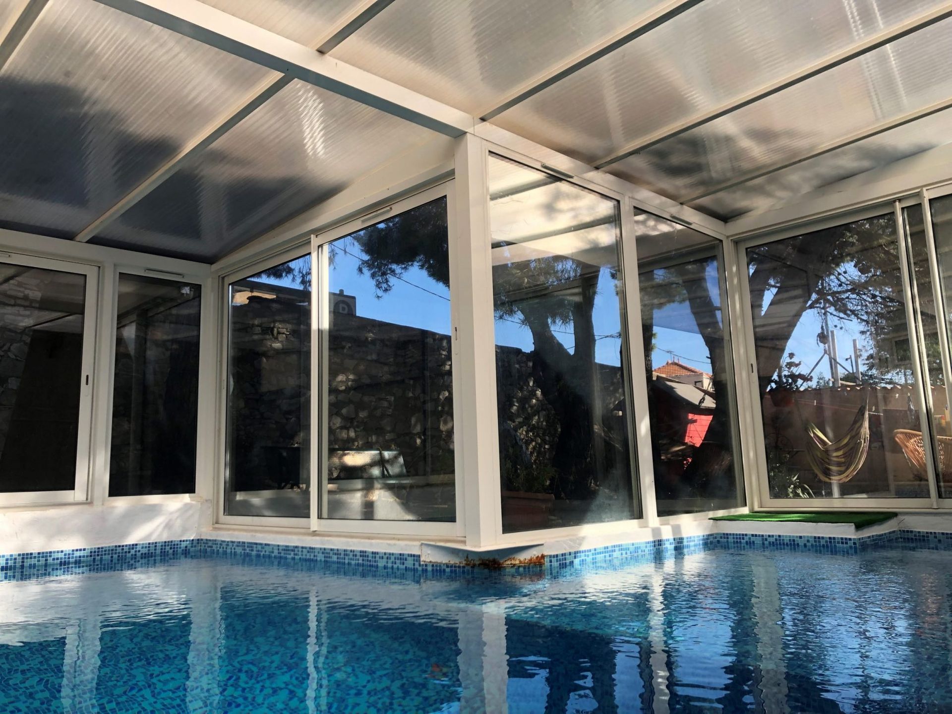 Une piscine dans une véranda, offrant une vue dégagée et une lumière naturelle.