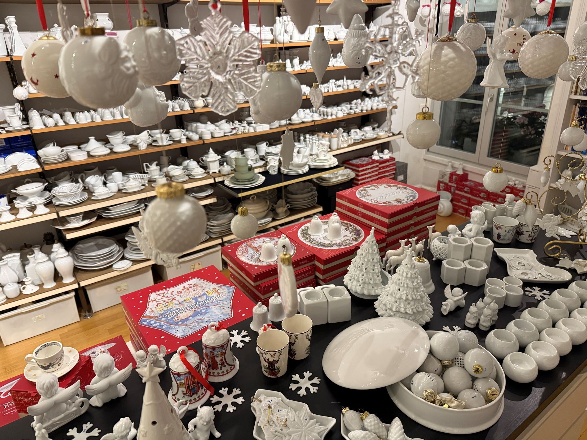 Ein Ladeninterieur, gefüllt mit weißer Weihnachtsdekoration und Geschirr auf Regalen und Auslagetischen.