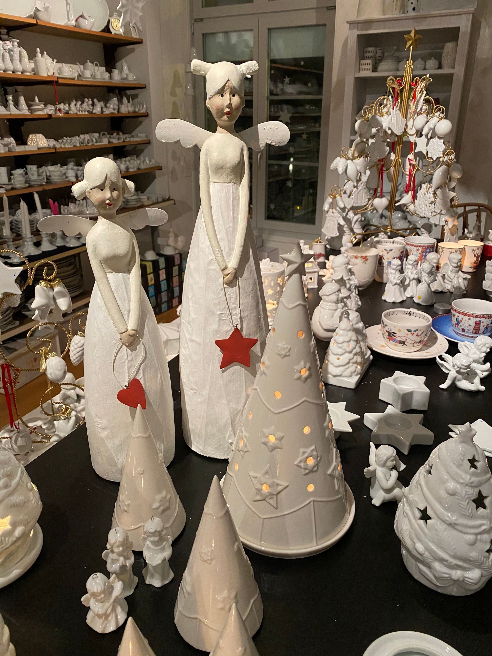 Eine Sammlung weißer Keramik-Weihnachtsengel und -bäume ist in einem Geschäft ausgestellt.