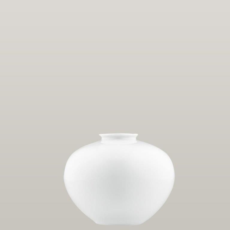 Weiße, runde Keramikvase mit kurzem Hals vor neutralem grauen Hintergrund.