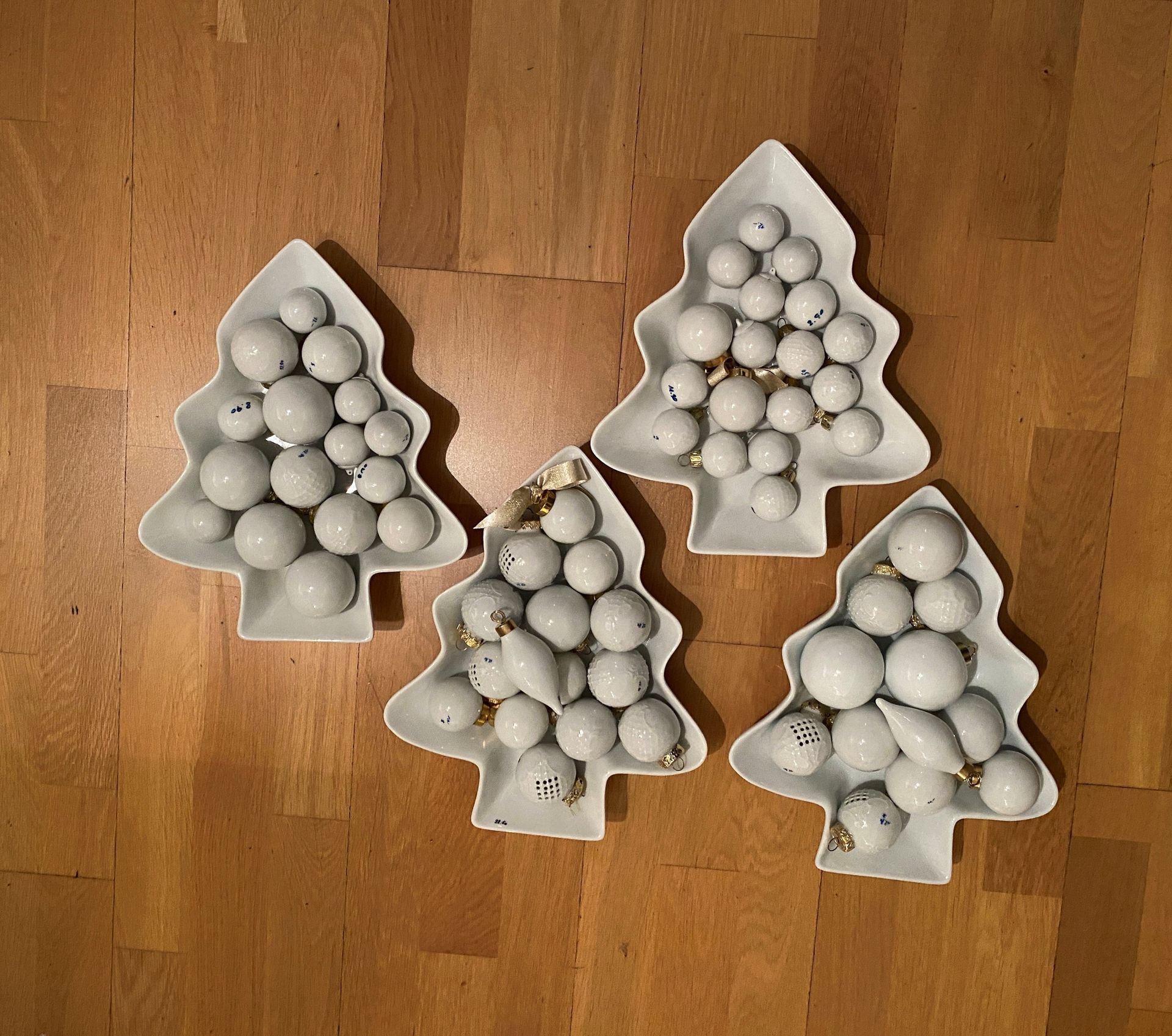 Vier weiße, baumförmige Schalen, gefüllt mit weißen Bonbons, auf einer Holzoberfläche.