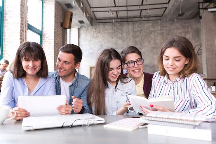 Un grupo de jóvenes está sentado en una mesa mirando una tableta.