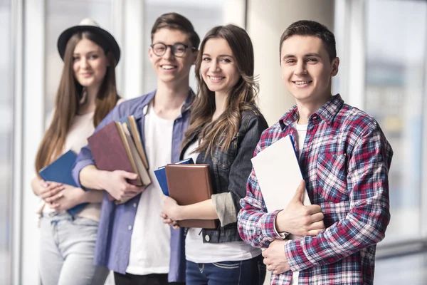 Un grupo de jóvenes de pie uno al lado del otro sosteniendo libros.