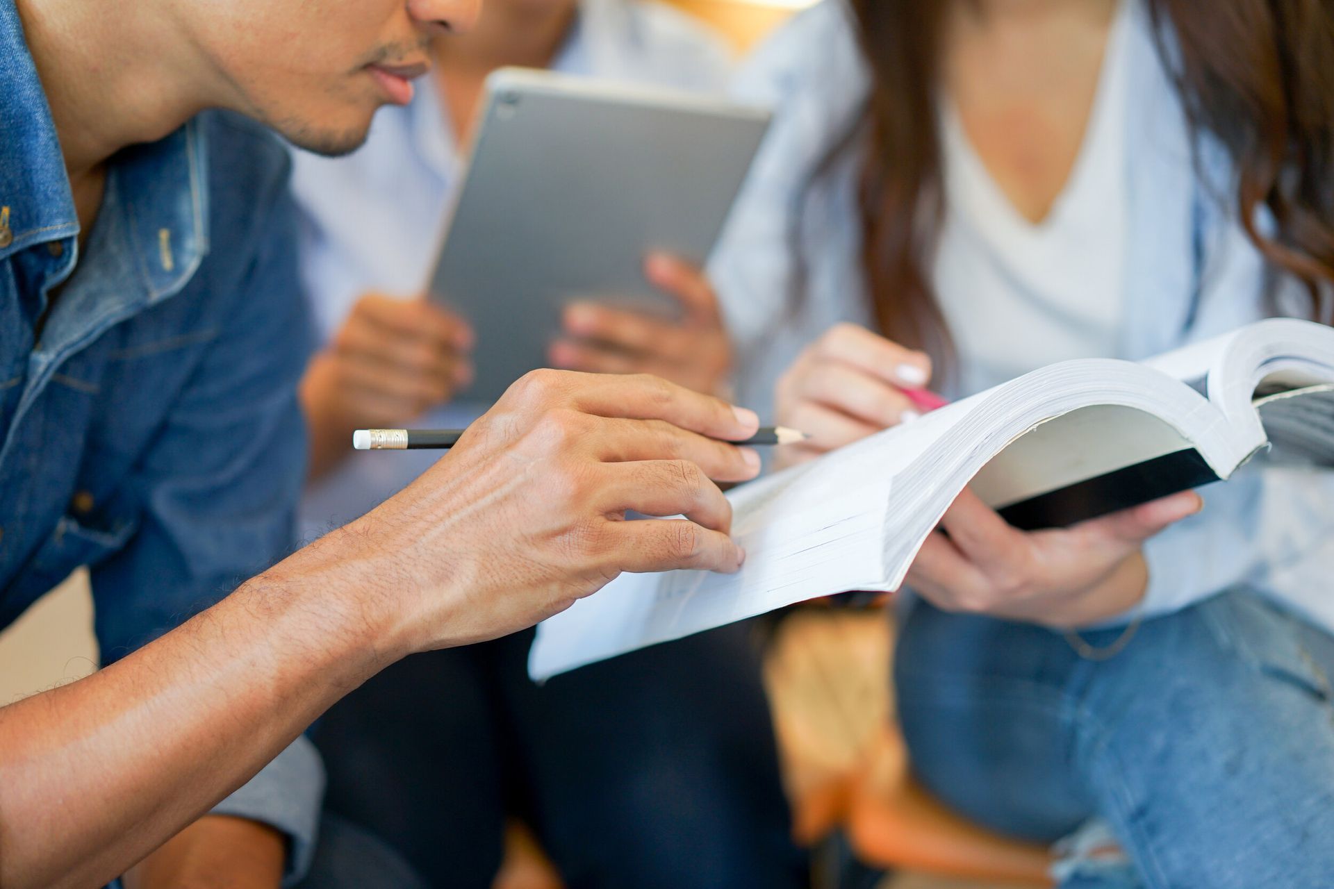 Un grupo de personas está mirando un libro y una tableta.