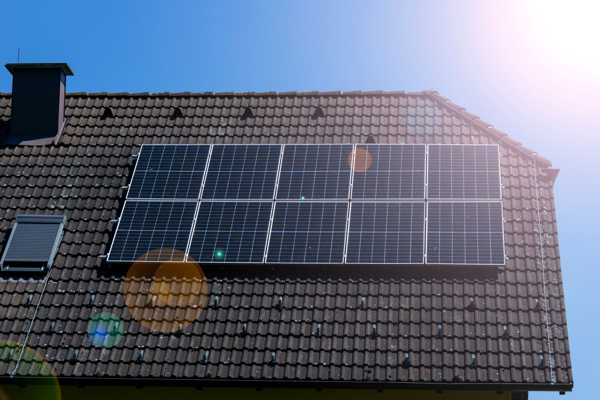 Des panneaux solaires installés sur le toit d'une maison en tuiles, sous un soleil éclatant.