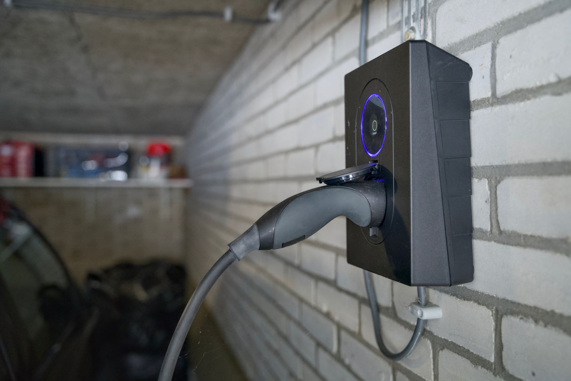 Borne de recharge pour véhicules électriques fixée sur un mur de briques.