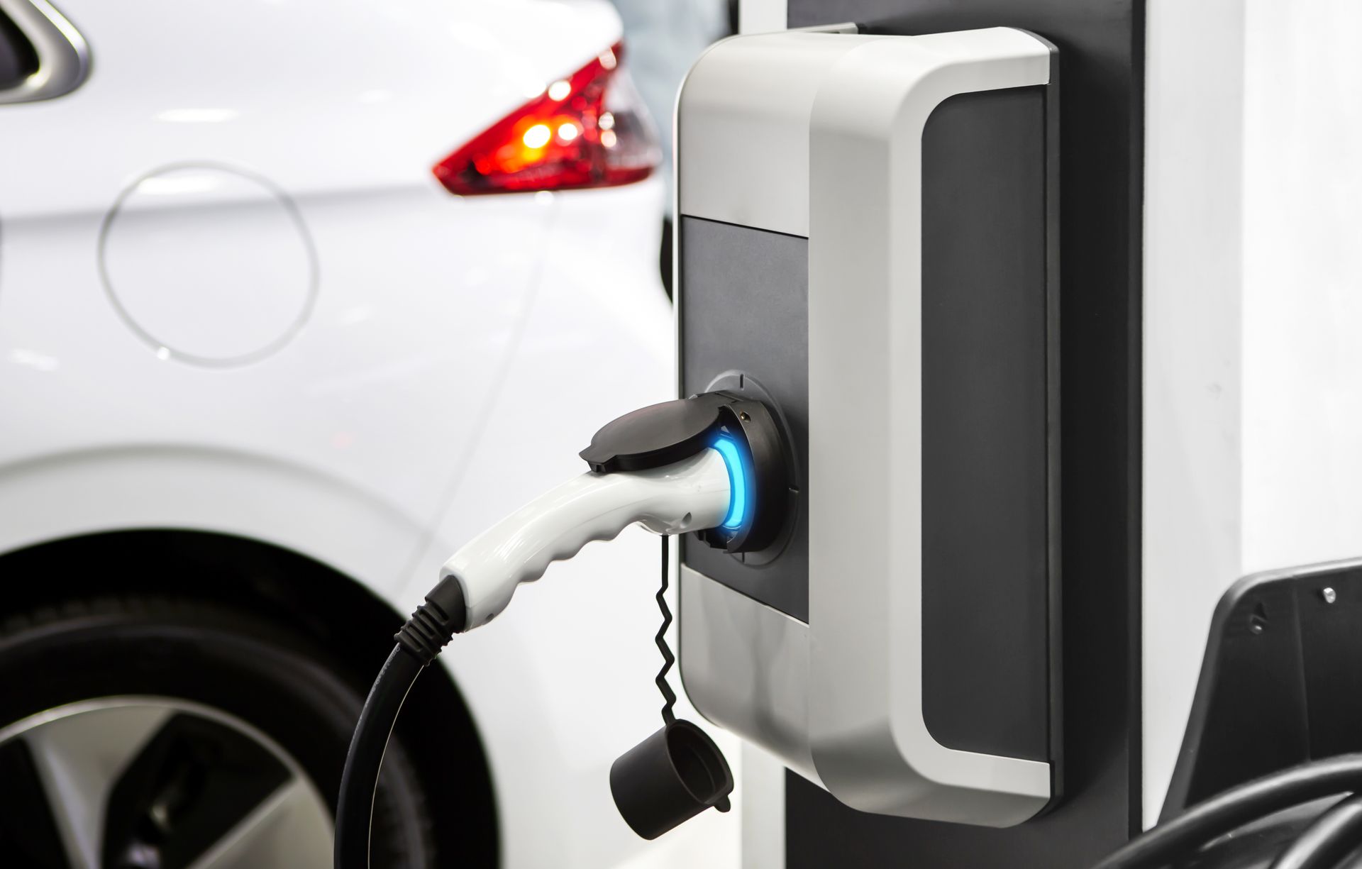 Voiture électrique en charge à une borne à côté d'un véhicule blanc.