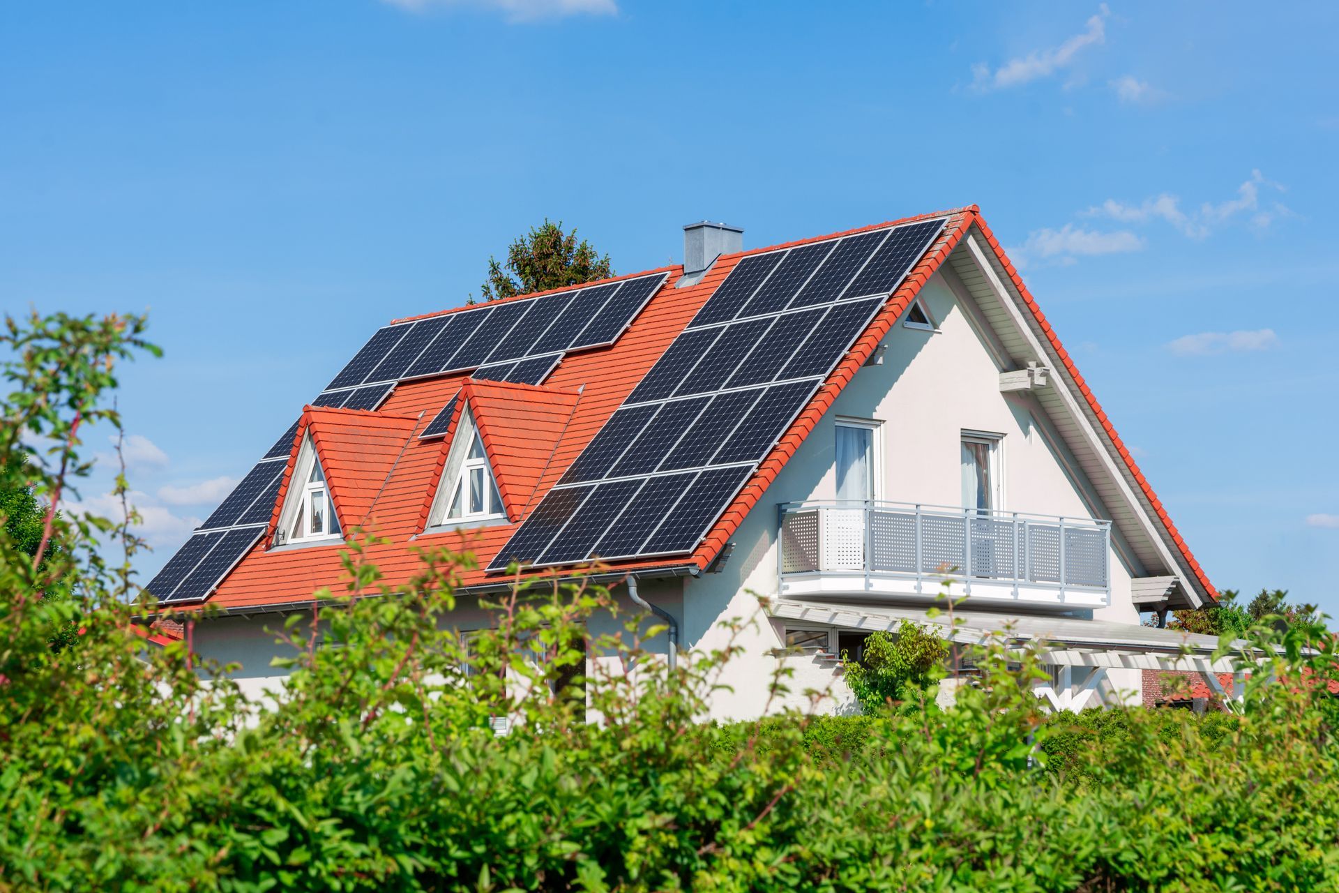 Maison avec panneaux solaires sur un toit rouge.