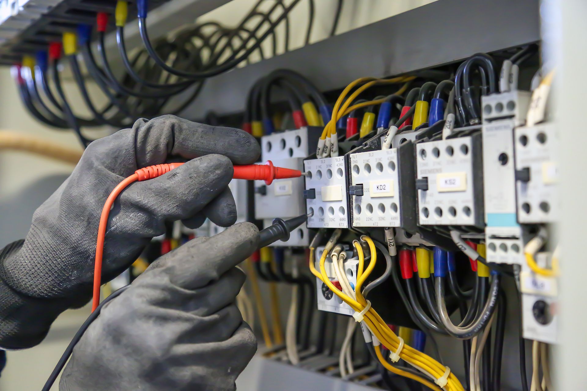 Un électricien travaille les branchements d'un tableau électrique. 