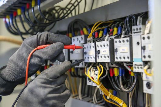 Un électricien travaille les branchements d'un tableau électrique.