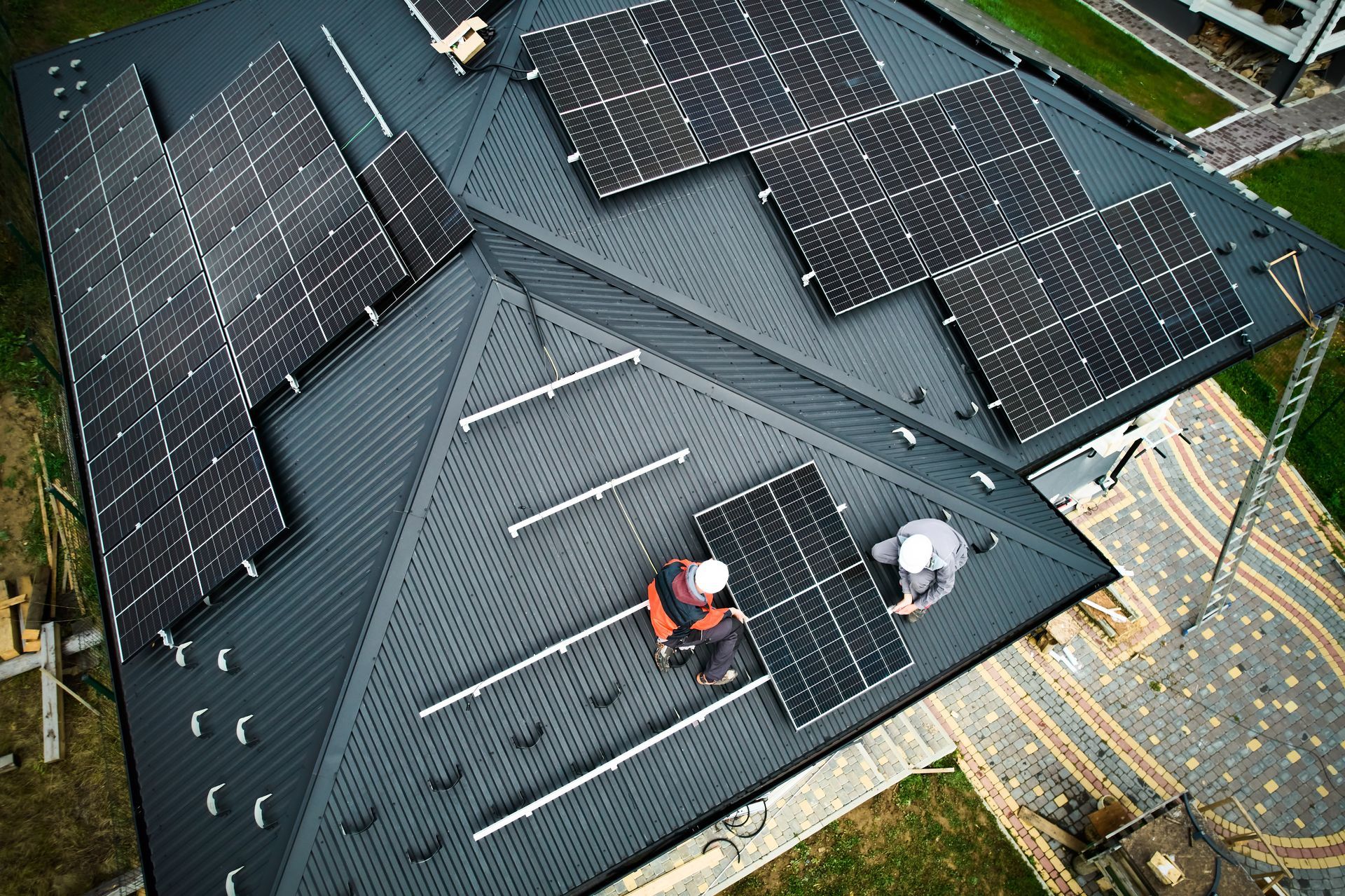 Des ouvriers installent des panneaux solaires sur un toit gris.