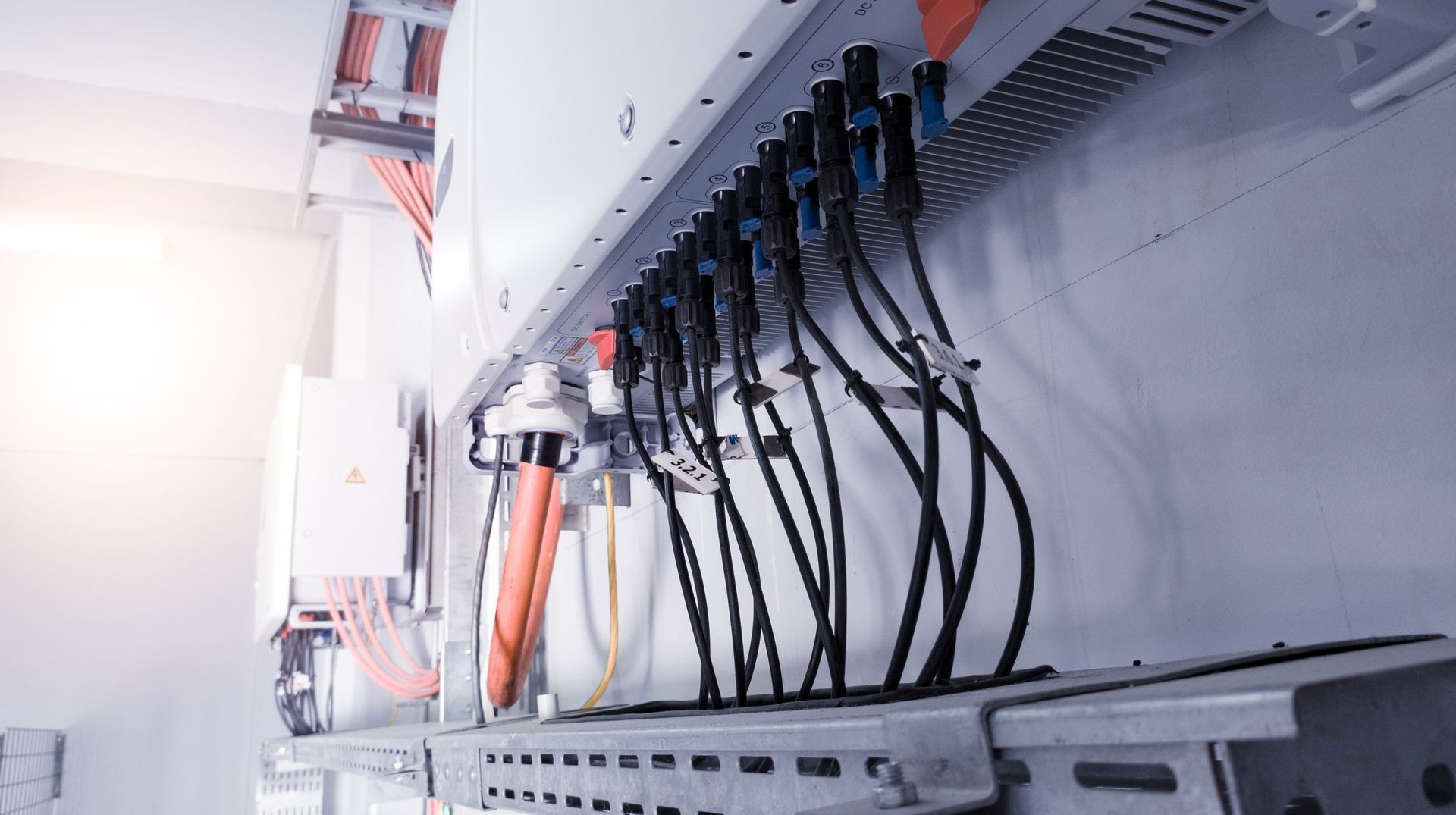 Gros plan sur un panneau solaire avec des câbles et des connecteurs noirs à l'intérieur d'un boîtier métallique.