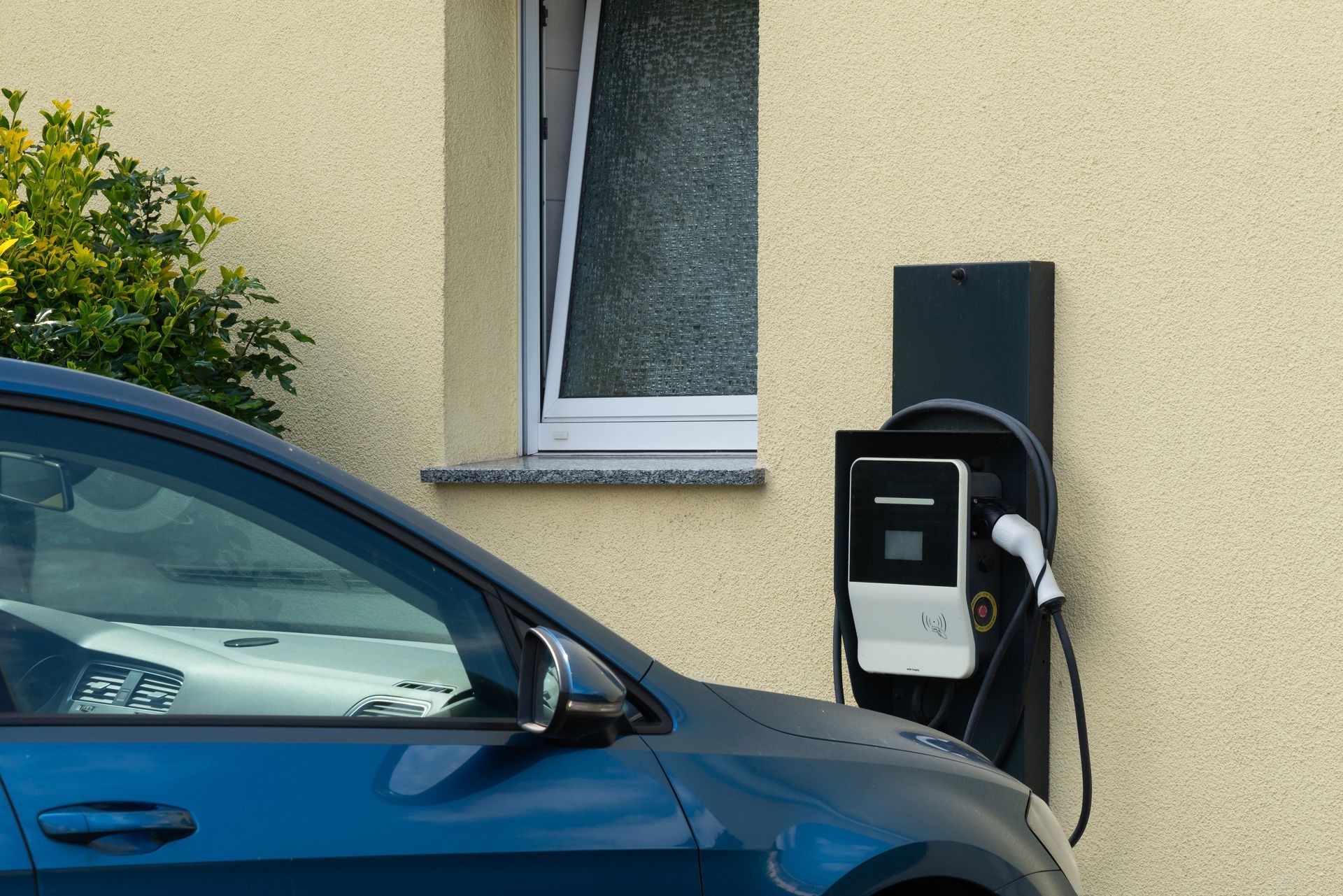 Voiture bleue branchée à une borne de recharge pour véhicules électriques.