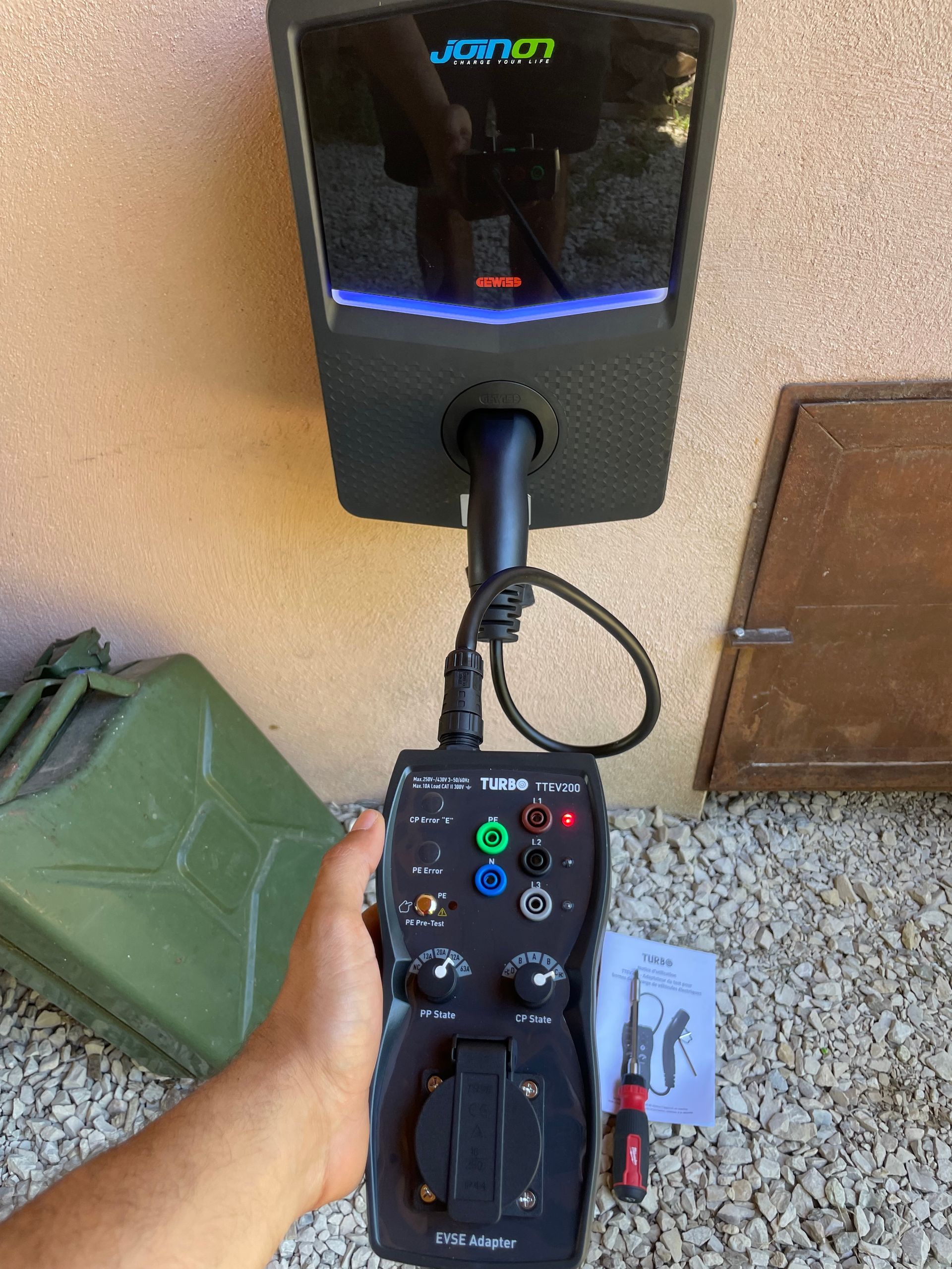 Main tenant une télécommande de programmation de borne de recharge.