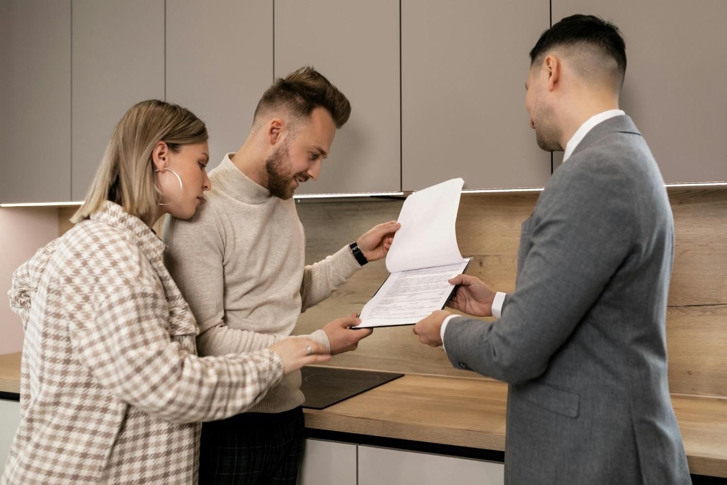 Tres personas en una cocina revisando documentos en un mostrador.
