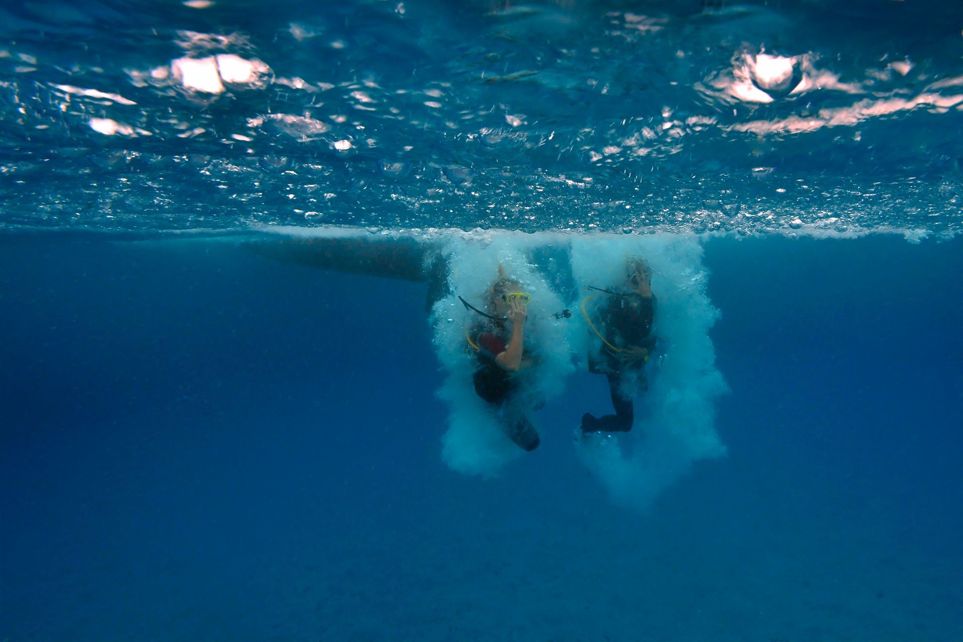 Dos personas están nadando bajo el agua en el océano.