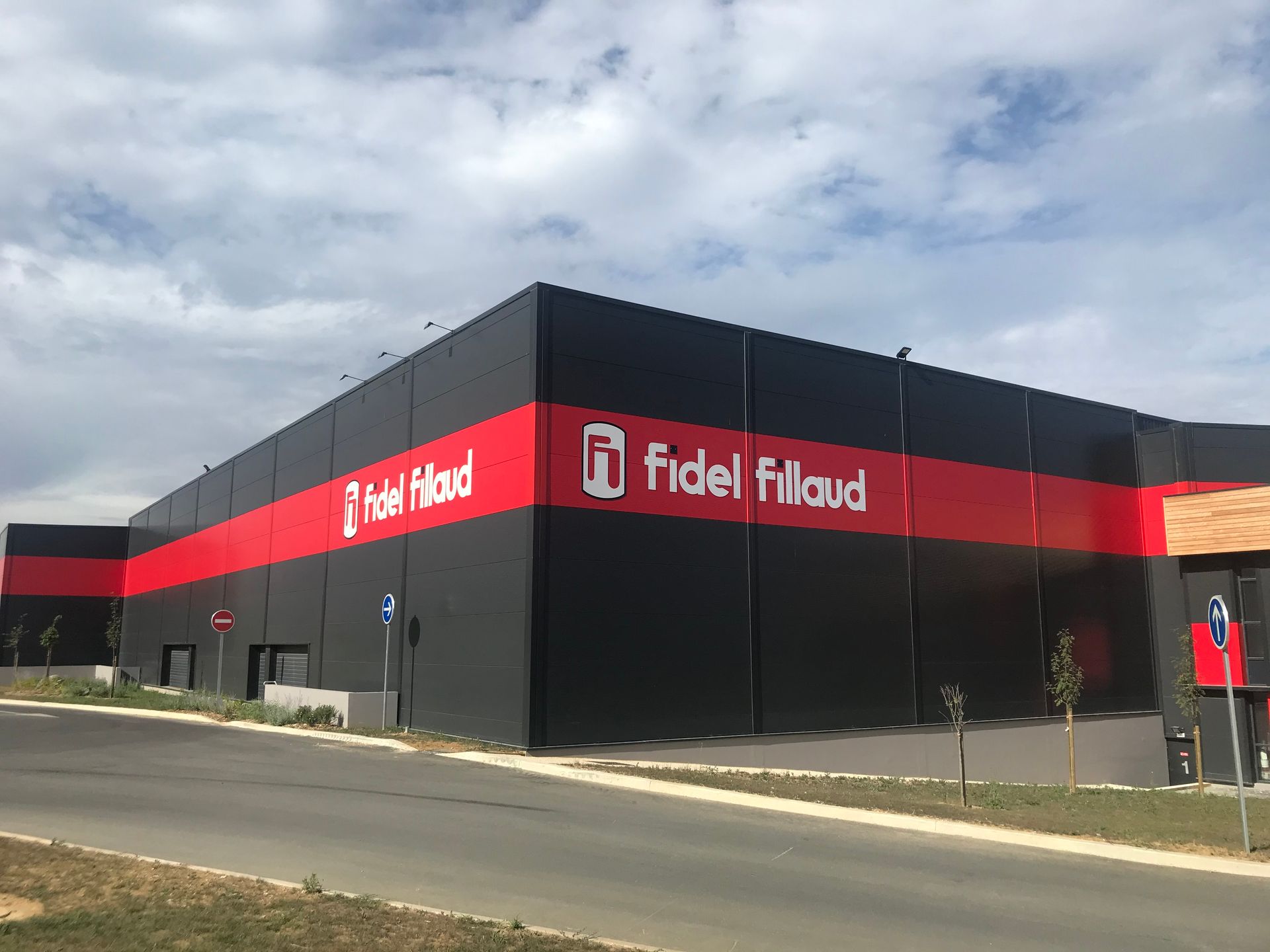 Un bâtiment industriel moderne, noir et rouge, avec le logo Fidel Filaud sur sa façade.
