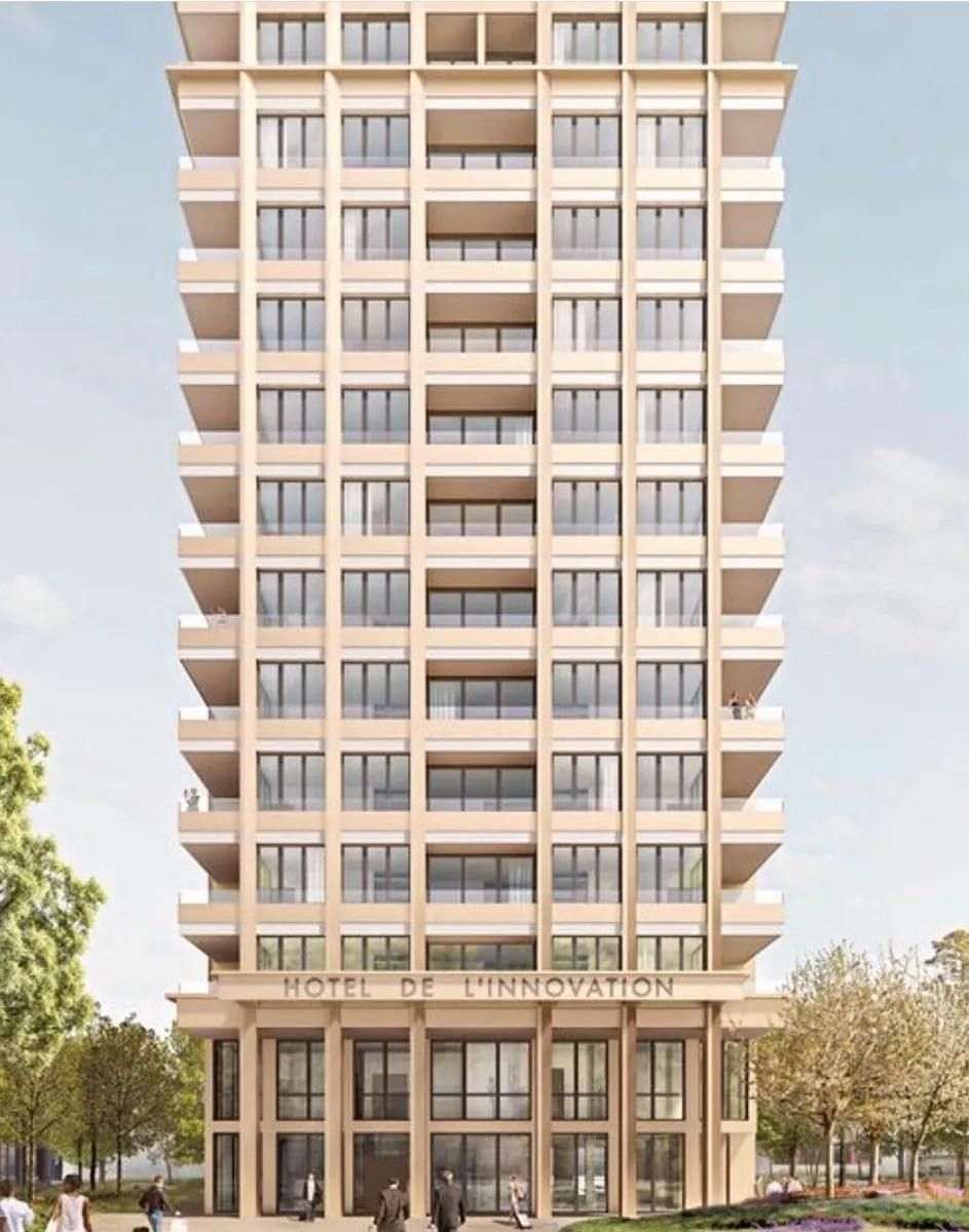 Immeuble de grande hauteur aux couleurs claires, enseigne « Hotel de l'Innovation » à sa base.