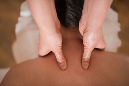Eine Person bekommt eine Massage mit den Händen auf dem Rücken.