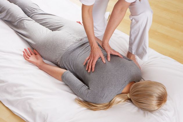 Eine Frau liegt auf einem Bett und bekommt eine Massage.