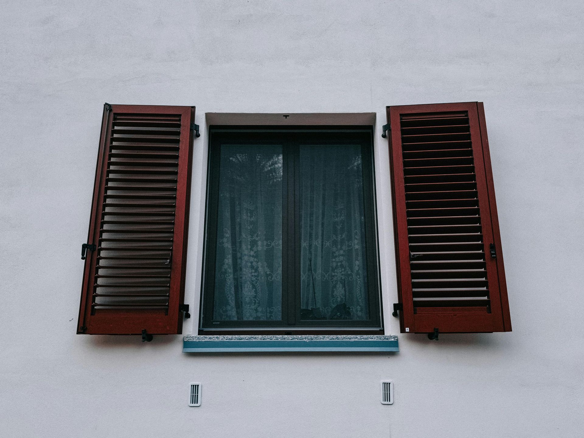 Volets battants de couleur rouge avec des ouvertures types persiennes