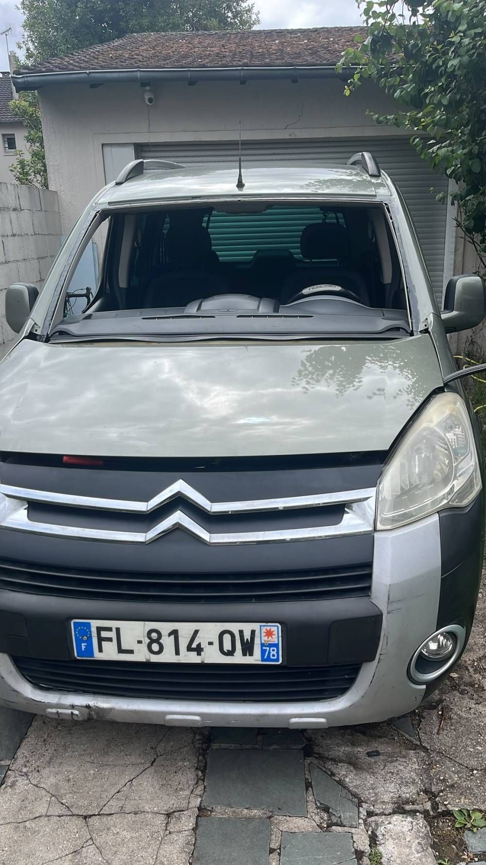 Camionnette Citroën argentée garée dans une allée, vue de face, avec le pare-brise endommagé.
