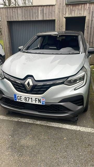 SUV Renault argenté garé devant un bâtiment en bois, dégâts visibles à l’avant