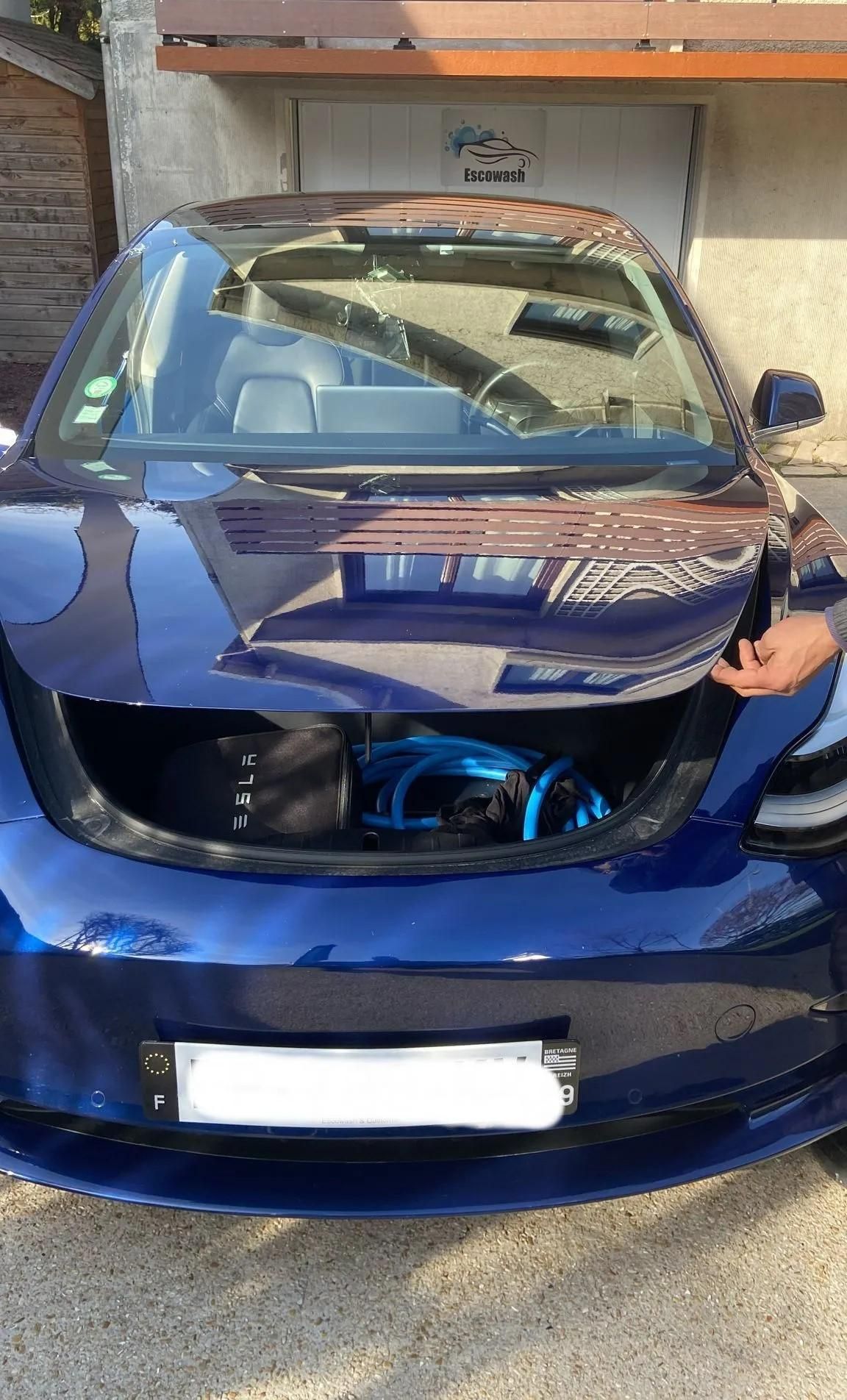 Voiture bleue avec l’avant fortement endommagé et le pare-brise brisé, garée devant un bâtiment