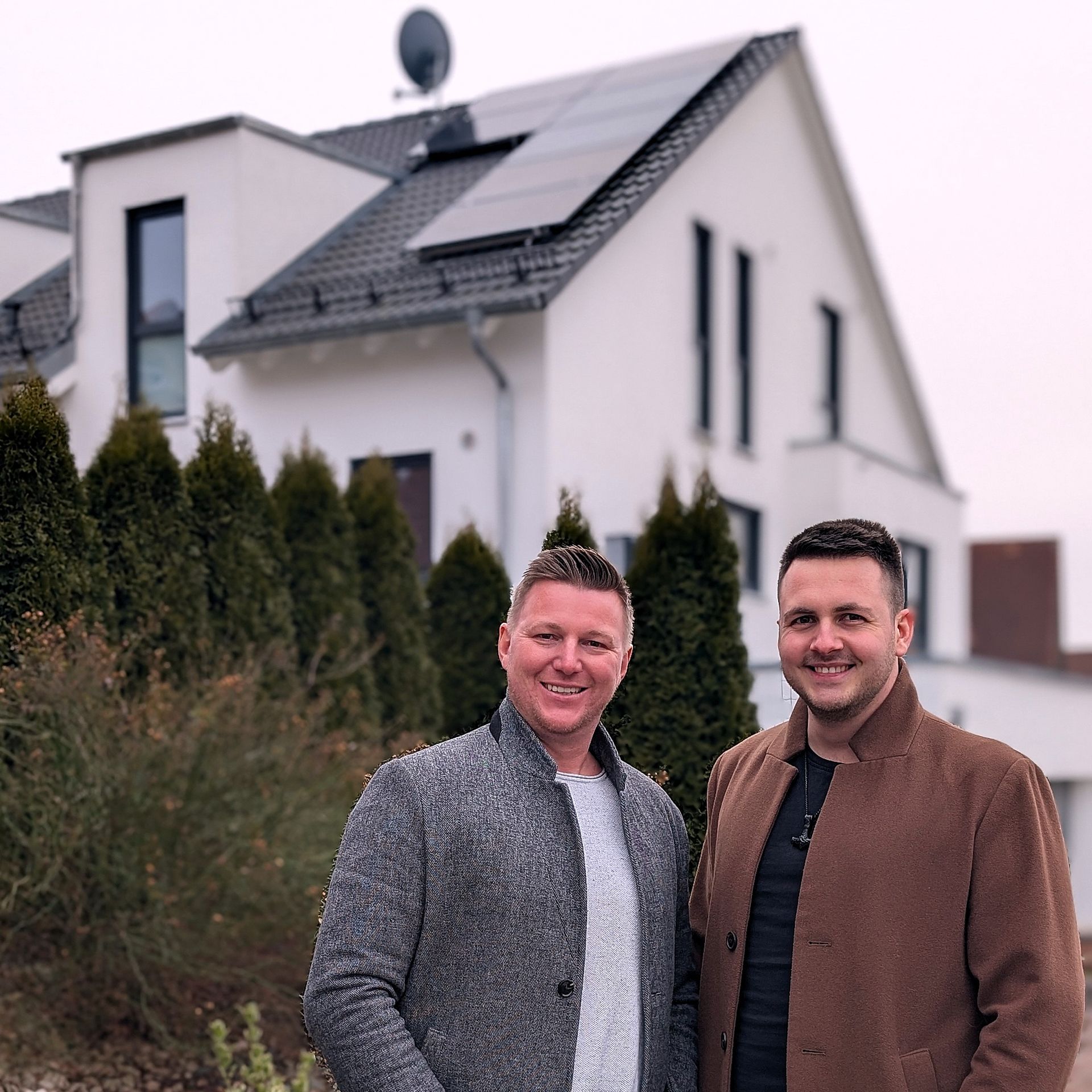 Zwei Männer stehen vor einem Haus mit Sonnenkollektoren auf dem Dach