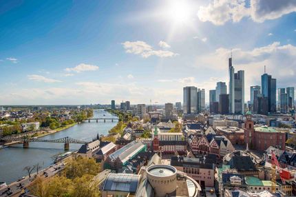 Eine Luftaufnahme einer Stadt mit einem Fluss im Vordergrund und einer Skyline im Hintergrund.