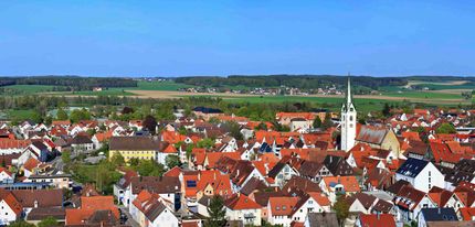 Eine Luftaufnahme einer kleinen Stadt mit roten Dächern und einem Uhrenturm.