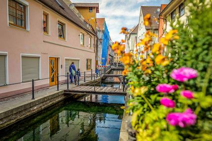 Ein Mann geht über eine Brücke über einen Fluss in einer Kleinstadt.
