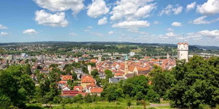 Eine Luftaufnahme einer von Bäumen umgebenen Stadt an einem sonnigen Tag.